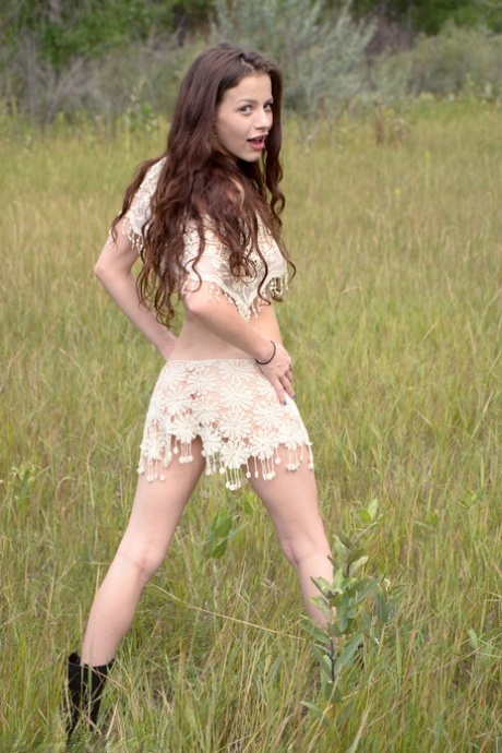 Young girl with long wavy hair Iva Nora gets naked in a field